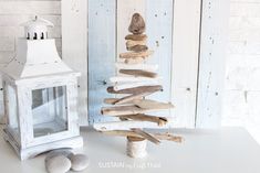 a small christmas tree made out of driftwood on a table next to a lantern