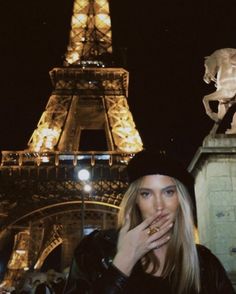 a woman standing in front of the eiffel tower at night with her hand on her mouth