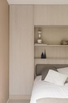 a bed sitting in a bedroom next to a shelf filled with bottles and vases