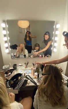 a woman standing in front of a mirror with her hair dryer and makeup brushes