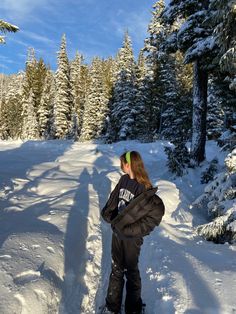 a woman standing in the snow with her back to the camera, wearing skis