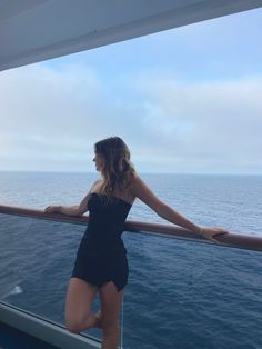 a woman standing on the deck of a ship looking out at the ocean from behind her