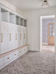 an empty room with white cabinets and wood flooring on the walls, in front of a large open door