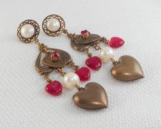 These Victorian Revival drop hearts earrings are stunning with a top faux Mabe pearl in a filigree circle, an open inverted etched heart with a dangle brass heart with a prong-set red stone, two dangle red glass hearts, a faux pearl bead and a bottom large puffy brass heart. They are spectacular!! measure 2 7/8 from the top of the wire to the bottom of the beads and measure 5/8 in width are pierced post earrings and light weight are in excellent condition and look awesome on! are so very beautif Retro Jewelry For Valentine's Day Party, Vintage Dangle Jewelry With Heart Beads, Vintage Dangle Heart Beads Jewelry, Vintage Jewelry With Heart Beads And Dangle Shape, Vintage Nickel-free Earrings For Valentine's Day, Nickel Free Vintage Earrings For Valentine's Day, Vintage Metal Heart Earrings For Valentine's Day, Dangle Pearl Earrings For Valentine's Day, Vintage Heart Charm Earrings For Valentine's Day