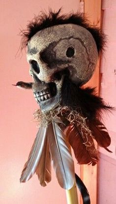 a creepy mask with feathers hanging from it's head and eyes on a hook