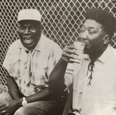 two black men sitting next to each other drinking soda and smiling at the same time