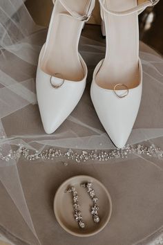 a pair of white high heels sitting on top of a table next to a plate