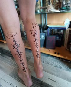 two people with tattoos on their legs standing next to each other in front of a bookshelf