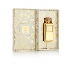 an open box with a bottle in it on a white surface and gold trimmings