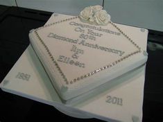 a wedding cake with white frosting and flowers on it's side, sitting on top of a table