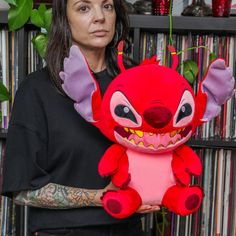 a woman holding a red stuffed animal in front of a book shelf