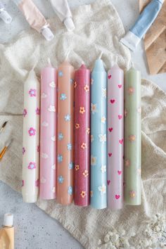 five different colored candles are lined up on a towel next to some scissors and other crafting supplies