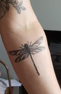 a woman's arm with a dragonfly tattoo on it