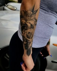 a woman with a tattoo on her arm holding onto a flower in front of a car