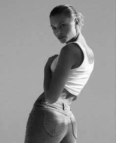 a black and white photo of a woman in high waist jeans posing for the camera