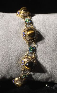 A very beautiful example of Chinese gold gilt on silver bracelet. This bracelet has bezel set round polished Tigereye stones With Enameling top and bottom and Flower links in between. Round tigereye cabochons measure 8mm with a Twist edge. There are 7 major links each set with Tigereye gold gilding all in tact . With 7 Alternate Enameled flower links . What a great gift for her absolutely near mint condition. Could become your family Heirloom . Get box with Purchase. Silver Rope Bracelet, Chinese Gold, Cameo Bracelet, Hartford Ct, Gold Girl, Bezel Set Diamond, Enamel Bracelet, Enamel Flower, Statement Bracelet