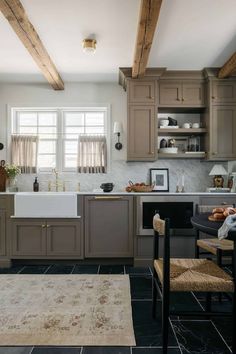 a kitchen with gray cabinets and white counter tops, an area rug on the floor