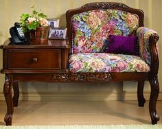 a chair with flowers on it next to a dresser and phone sitting on the end table