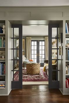 an open door leading to a living room with bookshelves and a rug on the floor