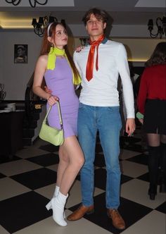 a man and woman are dressed up in costume for a halloween party, standing next to each other on a black and white checkered floor