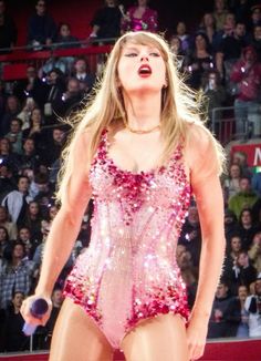 a woman in a pink bodysuit holding a tennis racquet on top of a court