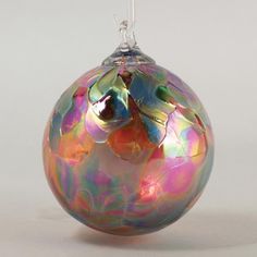 a glass ornament hanging on a white background with an orange and pink design