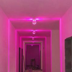 an empty hallway with pink lighting and white walls