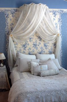 a white bed with blue and white wallpaper in a bedroom