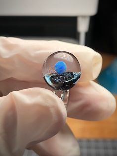 a person is holding a glass ball in their hand, with water inside the sphere