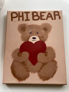 a brown bear holding a red heart on top of a wooden sign that says, phi bear