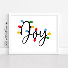 a white framed print with the word joy written in black and colorful lights on it