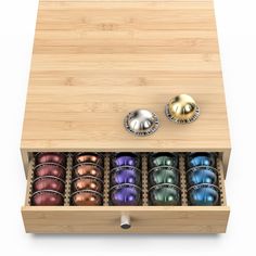 a wooden box with six different colored balls in it and two metal knobs on the lid