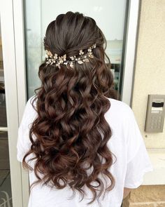 the back of a woman's head with long wavy hair and gold leaves on it