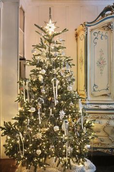 a decorated christmas tree in a room with white walls and gold trimmings on it