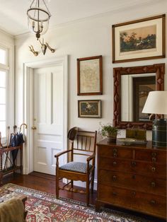 a living room filled with furniture and pictures on the wall next to a doorway that leads to a sitting area