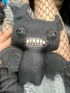 a person holding a black stuffed animal in their hand and netted stockings on the other side