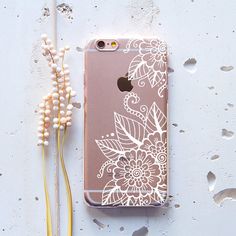 an iphone case sitting on top of a table next to some flowers and beads,