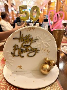 a 50th birthday cake sitting on top of a table with people in the back ground