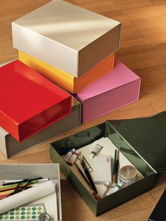 several different colored boxes on the floor with pens, scissors and pencils in them