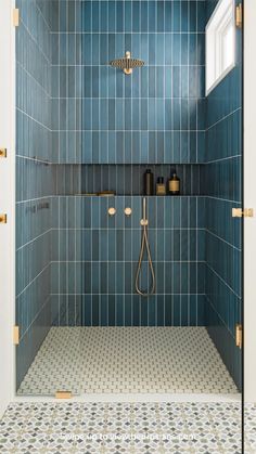 a blue tiled shower with gold fixtures and tile flooring in the shower stall area