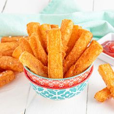 a bowl filled with cheetos sitting on top of a white table next to other foods