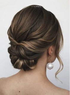 a woman with her hair in a low updo and pearls on the back of her head