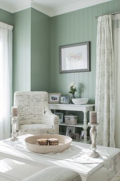 a living room with green walls and white furniture in the corner, including a chair