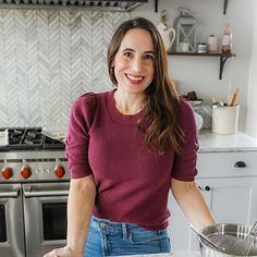 a woman standing in front of a kitchen counter with a pan on top of it