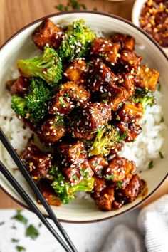 a bowl filled with meat and broccoli on top of rice next to chopsticks