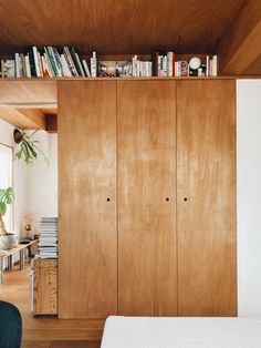 a bed sitting in a bedroom next to a wooden cabinet with books on top of it