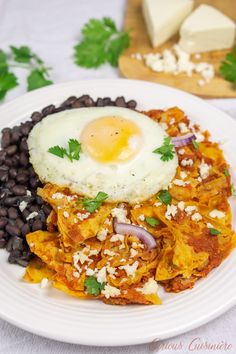 a white plate topped with black beans and an egg on top of hashbrowns