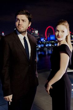 a man and woman standing next to each other in front of a cityscape