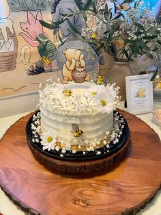 there is a cake on the table with flowers and bees around it in front of a painting