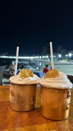 two ice cream sundaes sitting on top of a wooden table